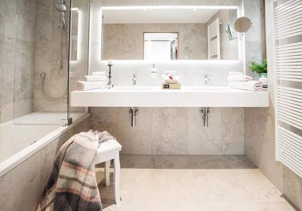 Ein weißes Badezimmer mit Badewanne, zwei Waschbecken und einen Kleien Sessel