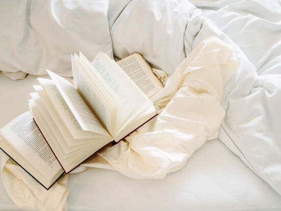 Three open books lie on the bed