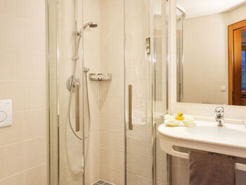 A shower in the corner of the room and a sink