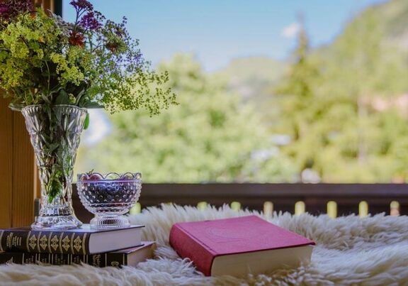 A stack of books and a bouquet of flowers on the balcony