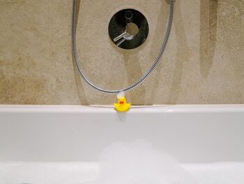 Eine Badente am Badewannen Rand mit Schaum im Gesicht