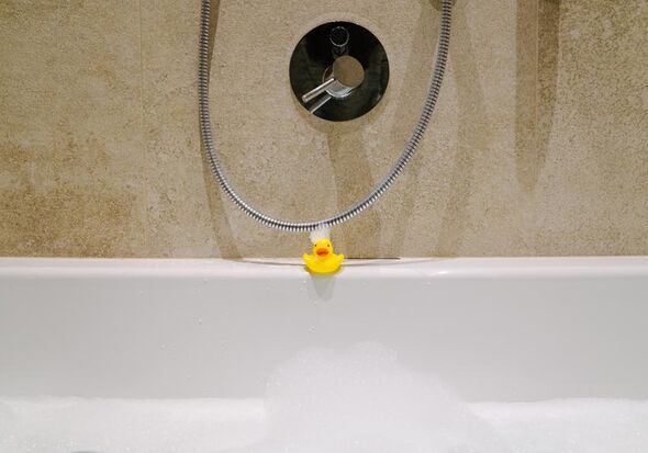 Eine Badente am Badewannen Rand mit Schaum im Gesicht