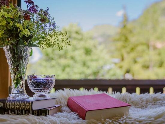 A stack of books and a bouquet of flowers on the balcony