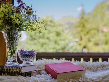 A stack of books and a bouquet of flowers on the balcony