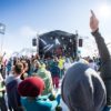 Viele Menschen mit guter Laune vor der Arlberg Music Festival Bühne. Im Hintergrund verschneite Berge