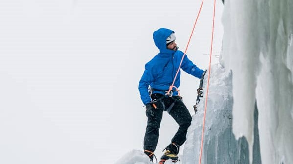 An ice climber with a blue jacket